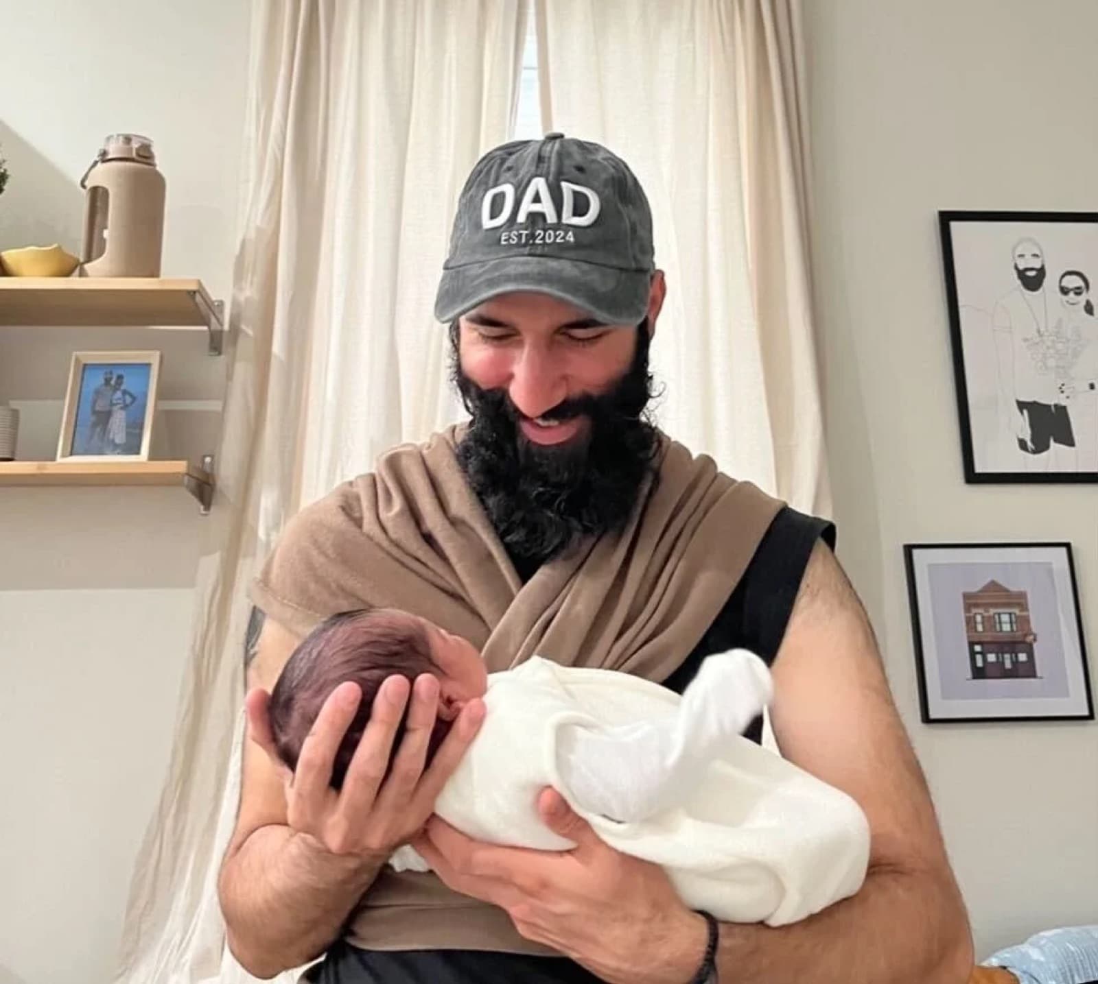 Craig in a DAD EST. 2024 hat, holding his newborn son Caiden